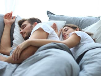 Happy couple sleeping in a comfortable bed at home