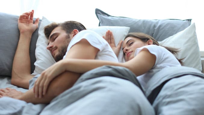 Happy couple sleeping in a comfortable bed at home