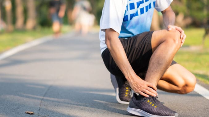 Young fitness man holding his sports leg injury.