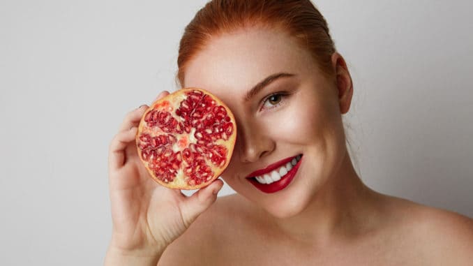 dreamstime_m_140560334 Beauty woman with orange pomegranate cut in half over white background. Attractive fresh vitamin concept