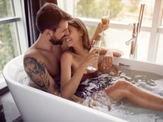 Beautiful young couple drinking champagne in the bathtub
