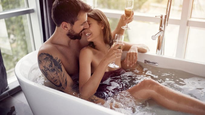 Beautiful young couple drinking champagne in the bathtub