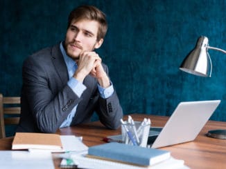 Shot of young man sitting at table looking away and thinking. Thoughtful businessman sitting in office