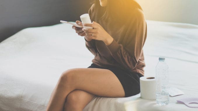 Woman using smart phone searching internet and reading drug or pill label and prescription medications,Health care concept,Close up and selective focus