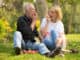 Happy senior couple relaxing in park eating apple together morning time.