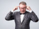 Senior man in suit and glasses holds fingers on temples, trying to remember or generate idea