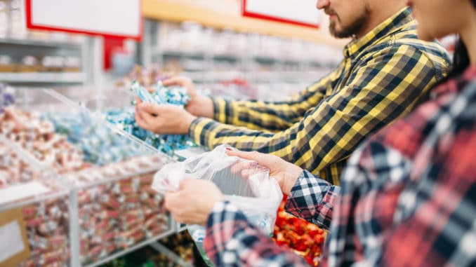 Happy couple buying sweets and candies in supermarket.