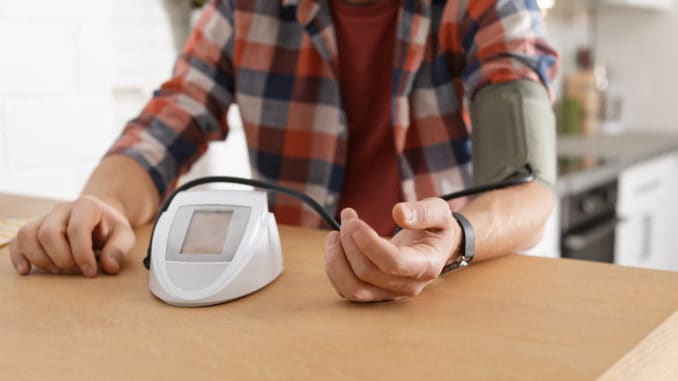 dreamstime_m_144786273 Man checking blood pressure with sphygmomanometer at table indoors, closeup.