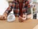 Man checking blood pressure with sphygmomanometer at table indoors, closeup.