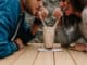 Happy young couple in love at cafe drinking a milkshake from same glass.