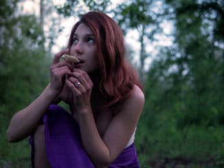 Young Beautiful Attractive woman in Purple Skirt in the forest with a hallucinogens mushroom at Mysterious Twilight.