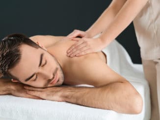 Handsome man receiving back massage on black background. Spa service