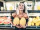 Young blonde woman holding two yellow melons in her hand