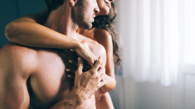 young couple kissing and playing in bedroom