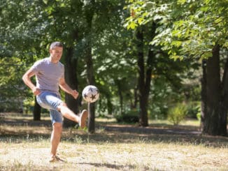 Handsome man playing football outdoors