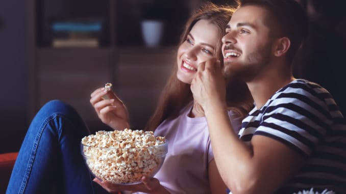 Young couple watching TV on sofa at night