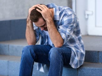 Stressed young man sitting on stairs outdoors