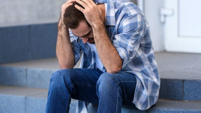 Stressed young man sitting on stairs outdoors