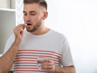 Young man ill with flu taking medicine at home