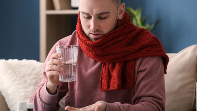 Young man ill with flu taking medicine at home taking medicine at home
