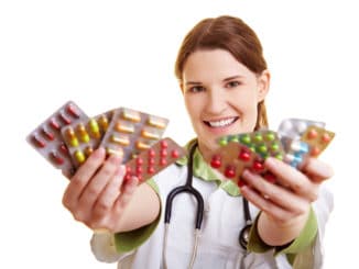 Smiling female doctor holding many colorful pills in her hands