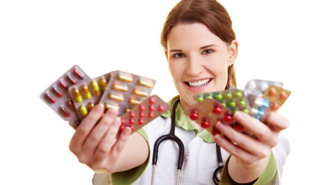 Smiling female doctor holding many colorful pills in her hands