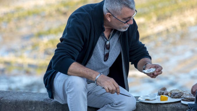 Man eating oysters bought on the seafront at Cancale