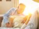 Sweet senior couple cuddling in bed with yellow lens flare in background