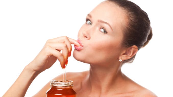 dreamstime_m_15915666 Attractive young adult with honey holding finger in the mouth isolated on white background