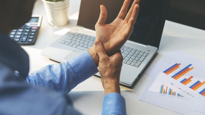 office syndrome - man suffering from wrist joint pain while working on laptop