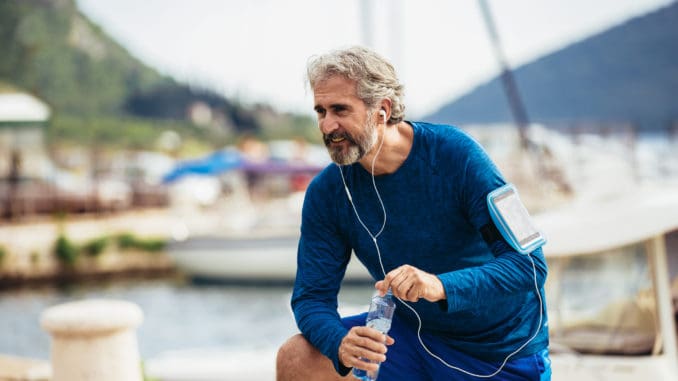 dreamstime_m_159592148 Fit thirsty senior man drinking water before running.