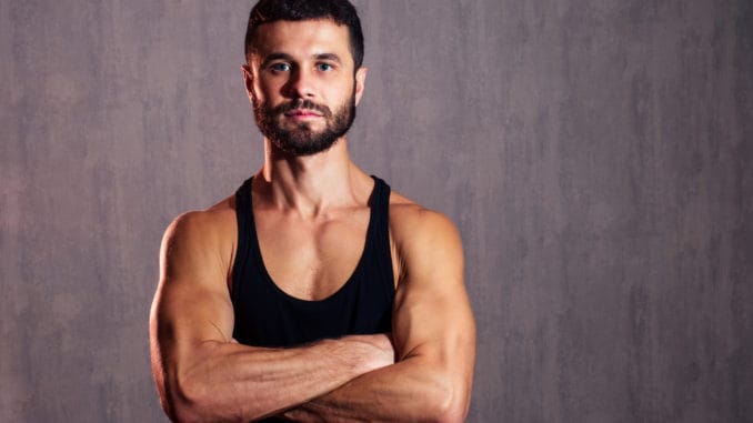 muscular healthy man in black T-shirt on dark background. concept of a healthy body and sexuality The mineral that boosts testosterone