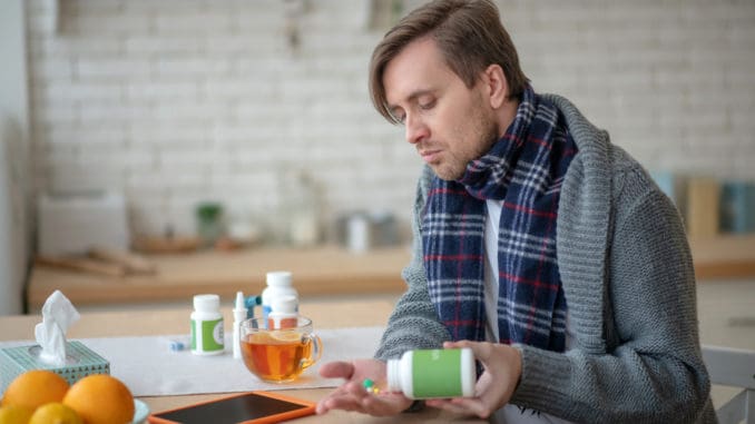 Sick man taking medication after drinking hot tea Man taking medication
