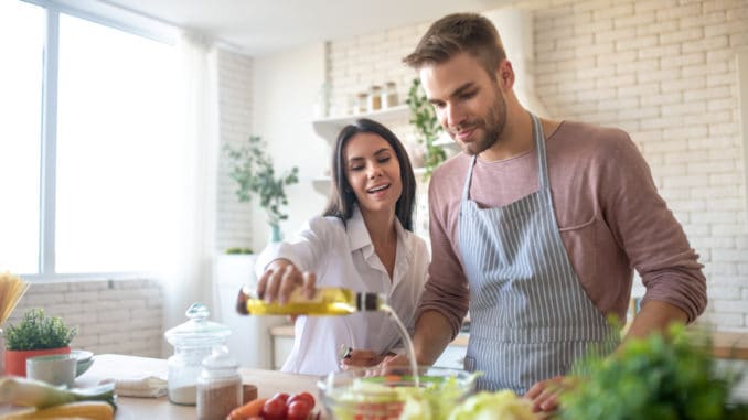 dreamstime_m_162368800 Adding olive oil. Beautiful young wife adding some olive oil to salad while cooking with husband