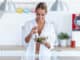 Shot of pretty young woman in underwear eating salad in the kitchen at home.