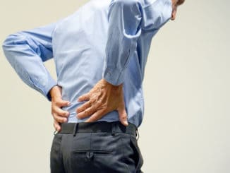 Old man with back ache clasping her hand to her lower back.