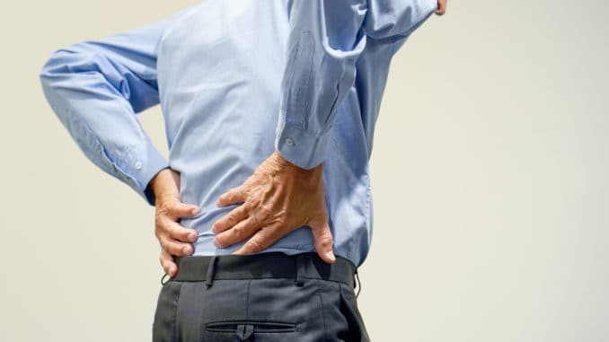 Old man with back ache clasping her hand to her lower back.