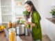 Smiling modern young housewife looking into the cooking pot