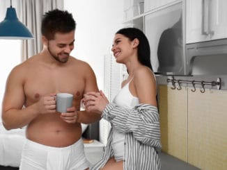 Young couple in white underwear drinking coffee at home