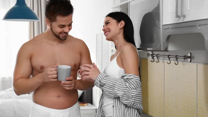 Young couple in white underwear drinking coffee at home