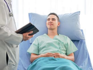 Young caucasian male patient on bed talking to doctor in hospital room, Health care and insurance concept