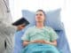 Young caucasian male patient on bed talking to doctor in hospital room, Health care and insurance concept