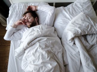 Bearded man sleeps restlessly in bed, he is alarmed and had a terrible nightmare.