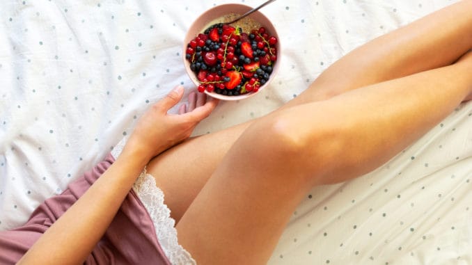 Woman eating oatmeal porridge with berries.