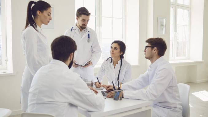 Group of doctors talking sitting at a table in the office of the hospital.