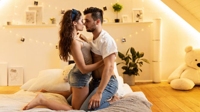 Beautiful passionate young couple hugging on the bed at home.