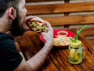 Young man eating a cheeseburger. Restaurant background