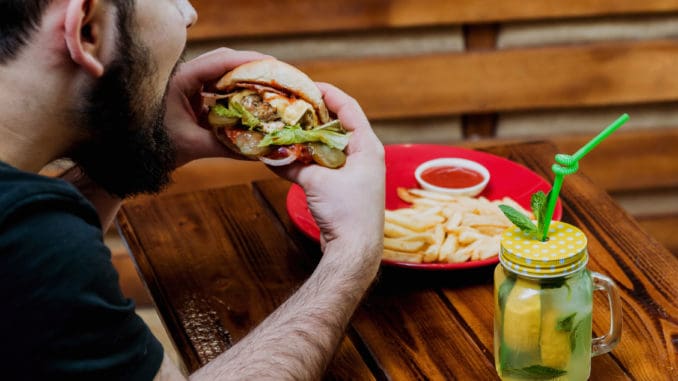 Young man eating a cheeseburger. Restaurant background