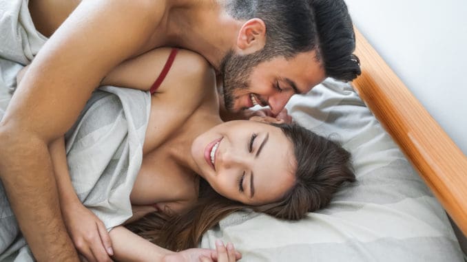 Happy couple having fun on bed under blanket -