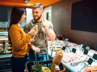 Family couple choosing oil for cooking fish in grocery store. Man and woman with cart buying beverages and products in market, customers shopping food and drinks